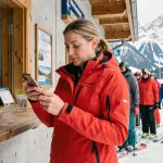 Skieuse comparant le prix d'un forfait journée et d'un forfait saison aux Deux Alpes au guichet d'une station alpine