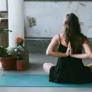 woman wearing black shirt sitting on green yoga mat