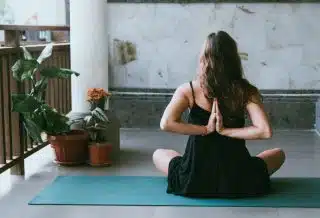 woman wearing black shirt sitting on green yoga mat