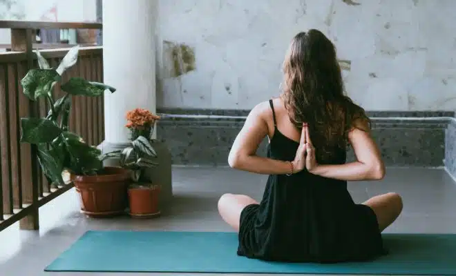 woman wearing black shirt sitting on green yoga mat