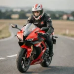 Jeune pilote en équipement de route sur une Aprilia RS 125 rouge sur route asphaltée en rase campagne