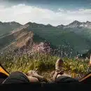 person lying inside tent and overlooking mountain